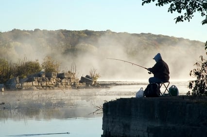 Fisherman by misty lake